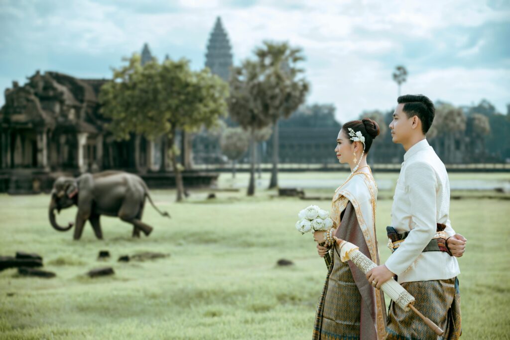 A couple in traditional attire standing in front of an elephant