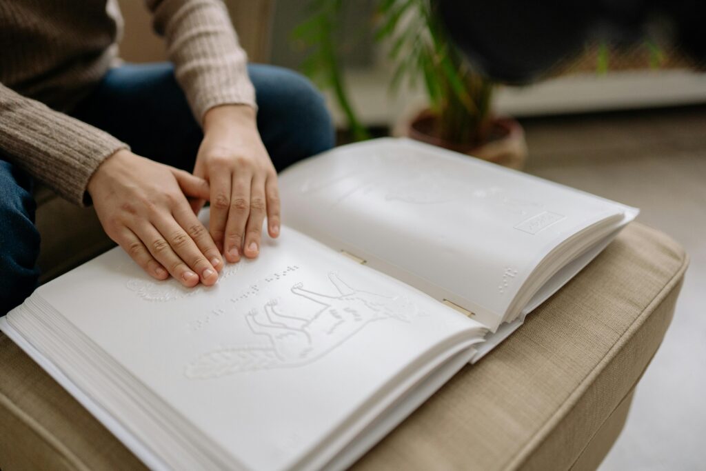 A Young Person Touching Drawings on a Braille Book